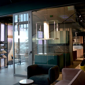 dwie lampy wiszące nad stolikiem kawowym, żółty fotel, pudrowy róż fotel, kuchnia, wyspa kuchenna, okap nad wyspą kuchenną, żaluzje, kanapa