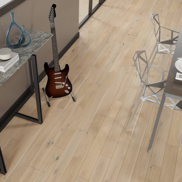 Czarne listwy przypodłogowe, stół z krzesłami, szare meble kuchenne, lampka na stoliku, kwiat w doniczce, gitara, duże okno balkonowe, drewniana podłoga