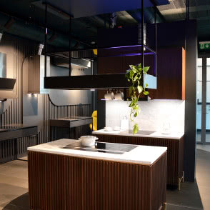 dwie lampy wiszące nad stolikiem kawowym, żółty fotel, pudrowy róż fotel, kuchnia, wyspa kuchenna, okap nad wyspą kuchenną, żaluzje, kanapa