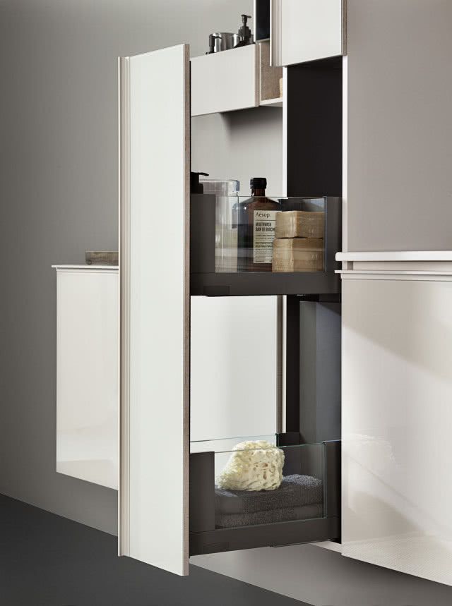 wysuwana szafka, białe fronty mebli łazienkowych, mydło w kostce, kosmetyki, ręczniki, myjka