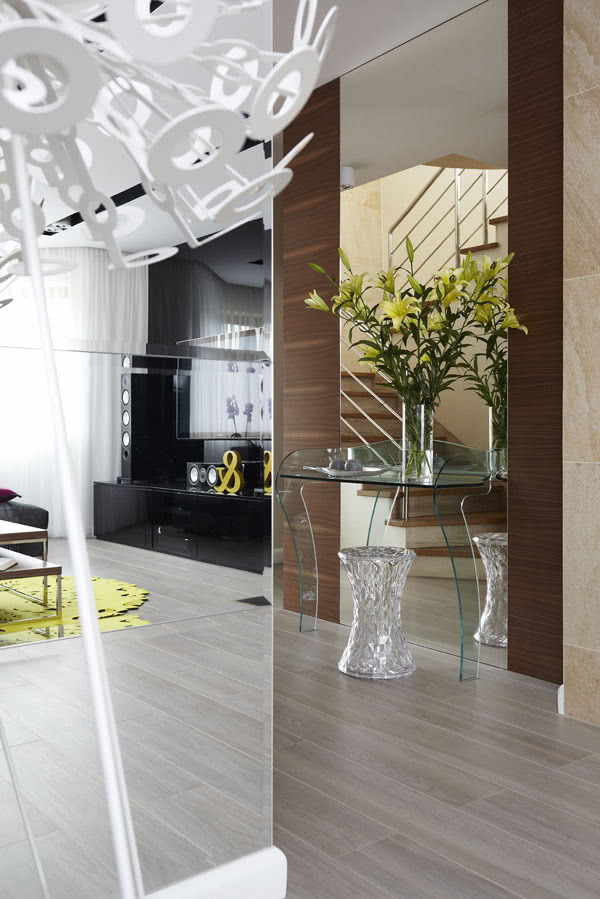 Pod wielkim lustrem w przedpokoju stoi szklana...