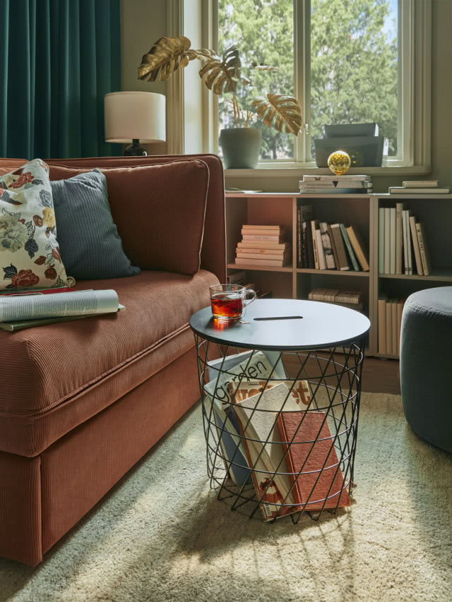 kosz z książkami obok brązowej sofy