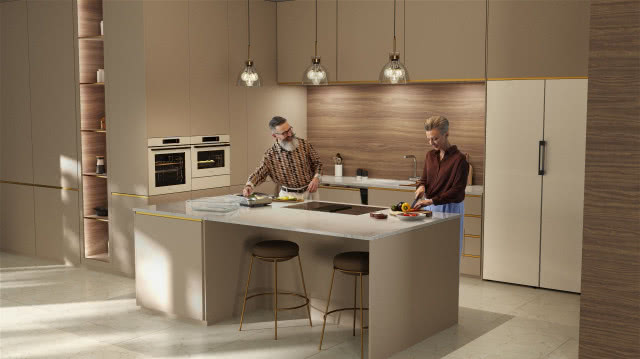 kremowe meble kuchenne, wyspa kuchenna, stołki barowe, piekarnik, płyta grzewcza, bateria zlewozmywakowa, oświetlenie sufitowe nad wyspą