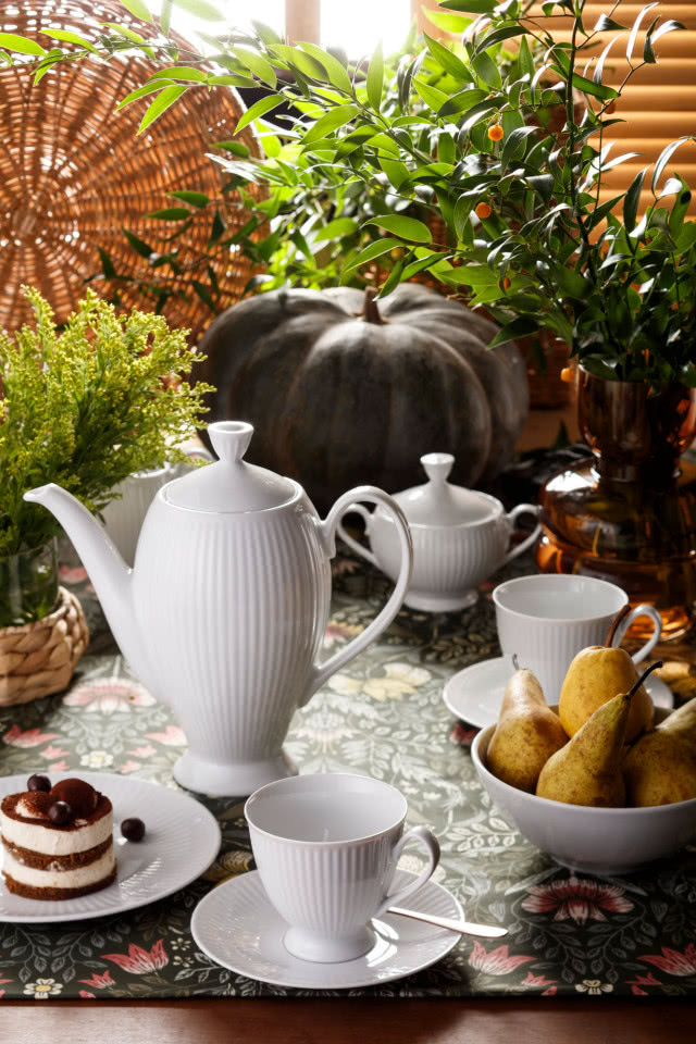 porcelana Dalia biała, drewniany stół obrus, kwiaty w wazonach, dynia, ciasto, wiklinowe ozdoby