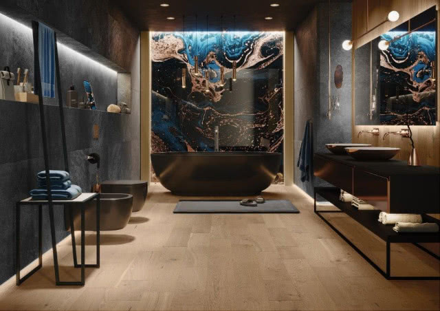 wanna wolnostojąca, drewniana podłoga, umywalki nablatowe, duże lustro, czarne meble łazienkowe, sedes, bidet, stolik