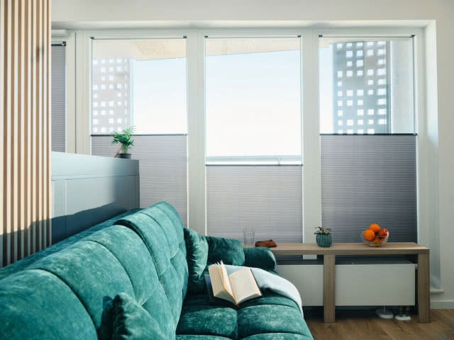 żaluzje plisowane przyciemniające, zielona kanapa, lamele, stolik kawowy