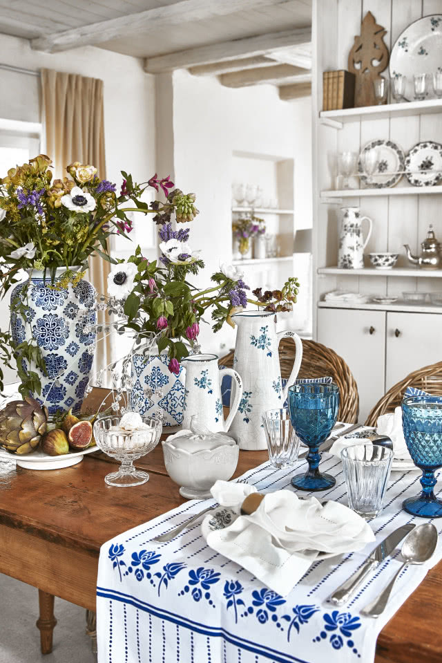 Rustykalna kuchnia w bieli i drewnie z biało-niebieską ceramiką.