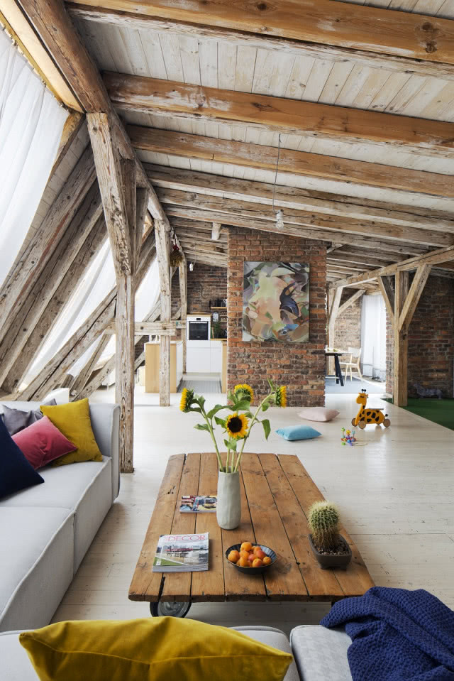 Świeże kwiaty i kolorowe detale we wnętrzu, drewniany sufit podparty belkami, stolik drewniany na kółkach