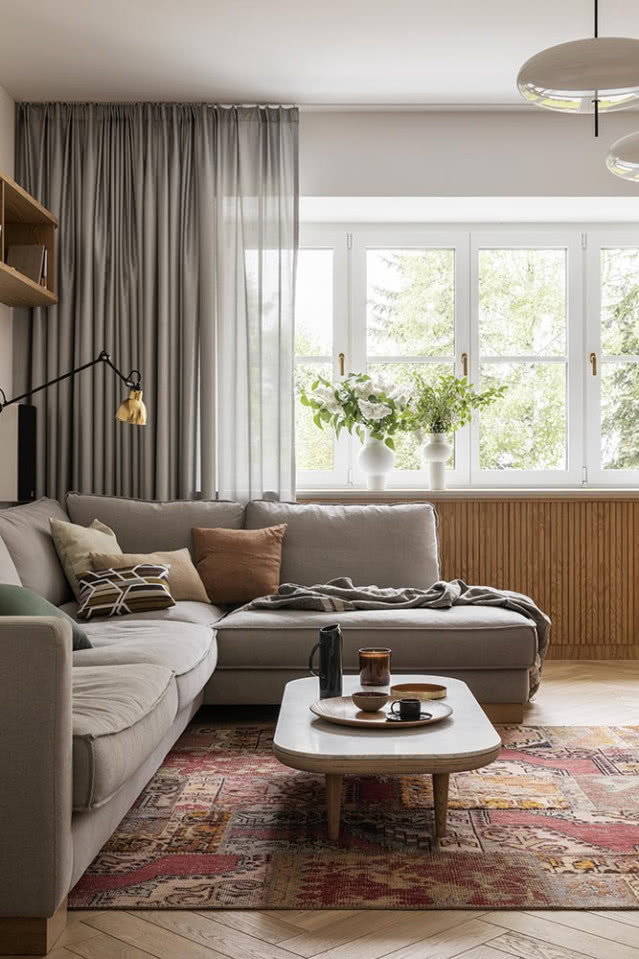 Salon z szarą kanapą i drewnianą podłogą