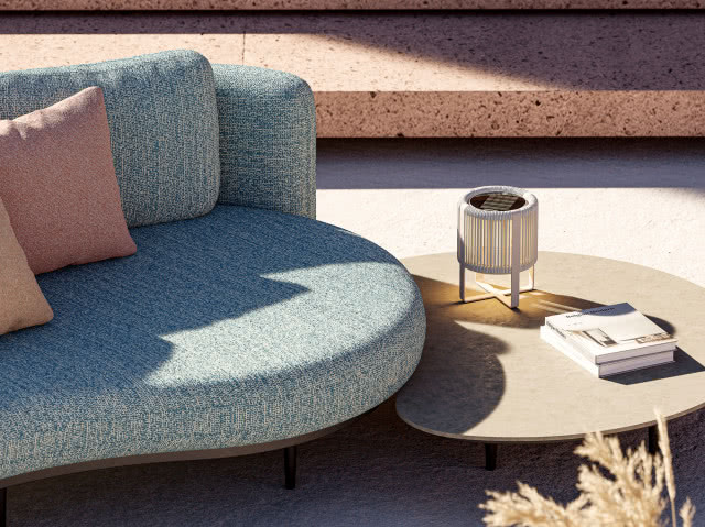 kanapa. poduszki ozdobne, stolik, lampa na stoliku, książki, schody