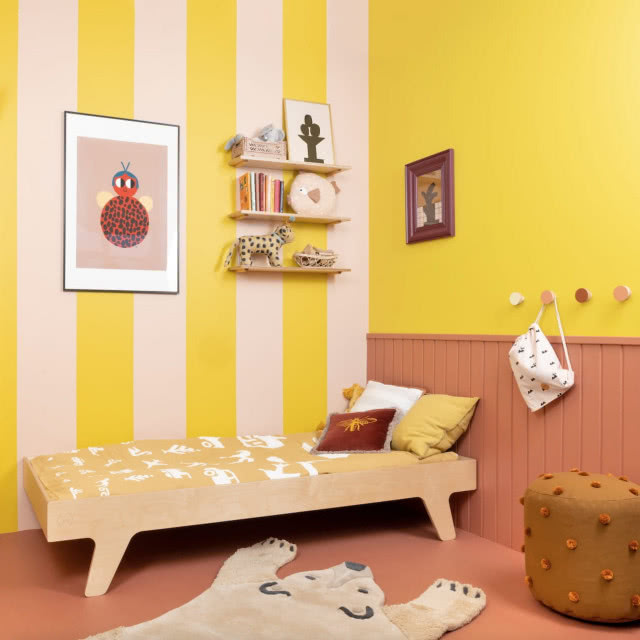 łóżko z naturalnego drewna na tle tapety w żółte pasy
