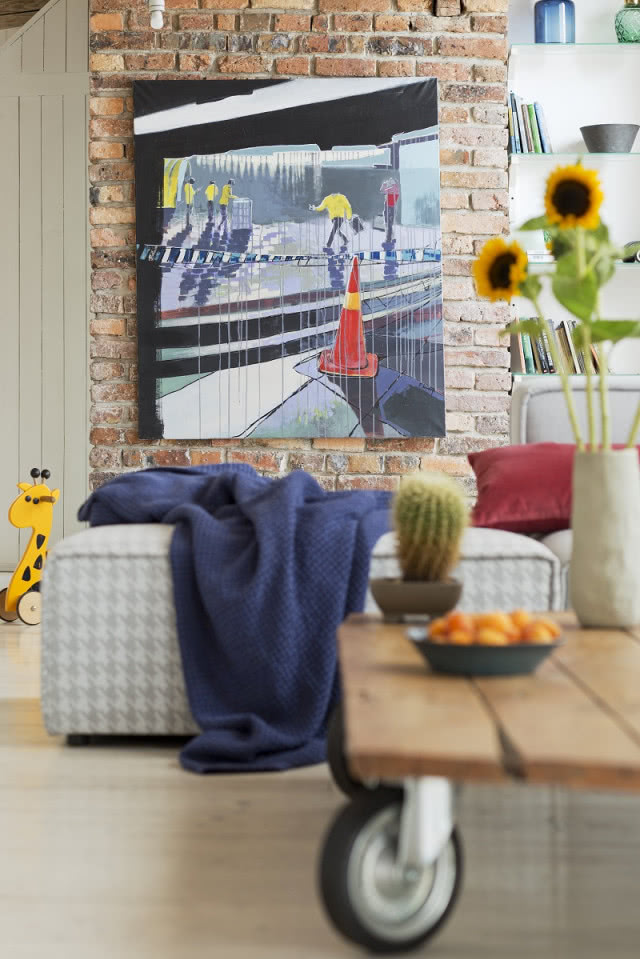 Wiosenne detale we wnętrzu, granatowy pled, słoneczniki, naturalna cegła na ścianie