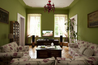 Kanapy w kwiaty i zielone sciany w rustykalnym salonie