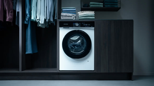 Pralko-suszarka Siemens iQ700 z pompą ciepła w eleganckiej domowej pralni, zabudowana wśród szaf i garderoby.