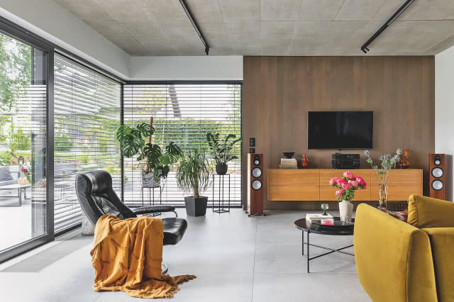 salon z żelbetowym sufitem i dużymi przeszkleniami