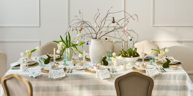 podłużny stół suto zastawiony na beżowym obrusie w paski