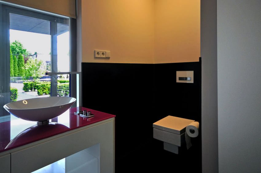 Z czarną ścianą kontrastuje biała szafka...