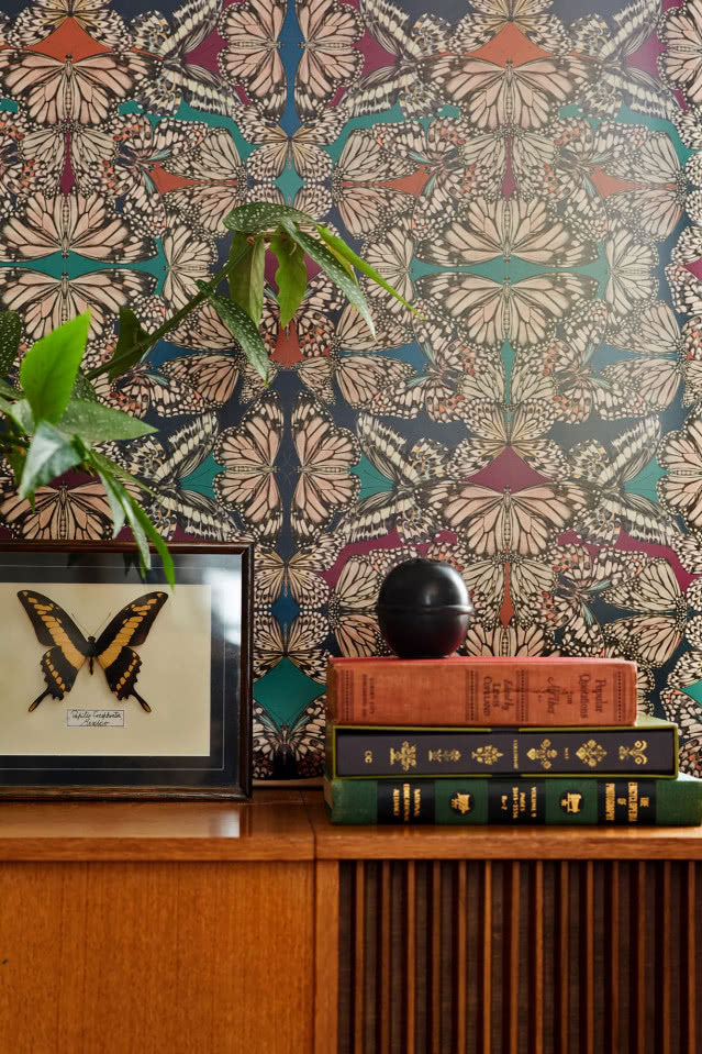 ciemna drewniana komoda na tle wzorzystej tapety