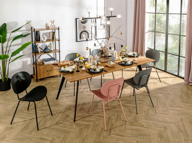 stół Venetti, czarne metalowe nogi, krzesła, jodełka na podłodze, duży kwiat w doniczce, obrazy, oświetlenie sufitowe, szafka z półkami, duże okno