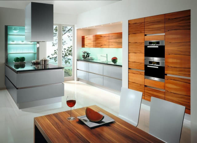 Venezia Monza, szafki dolne z frontami Monza z laminatu metallic, szafy wysokie i wiszące z frontami Catania, fornirowanymi naturalnym drewnem jabłoni indyjskiej, fronty uchylne szafek wiszących otwierane elektrycznie, blaty z konglomeratu, Sachsen Küchen GmbH, PERFECT LINE KUCHNIE & WNĘTRZA