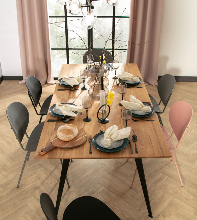 stół Venetti, czarne metalowe nogi, krzesła, jodełka na podłodze, duży kwiat w doniczce, obrazy, oświetlenie sufitowe, szafka z półkami, duże okno