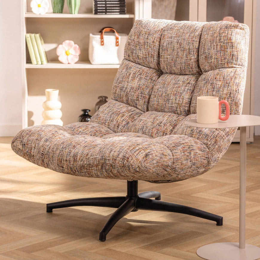 Fotel Derixi z obrotową podstawą i tapicerką w stylu retro w jasnym salonie z drewnianą podłogą i nowoczesnymi dodatkami.