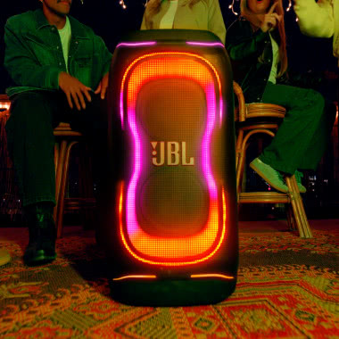 JBL PartyBox 330 z podświetleniem LED podczas domowej imprezy w otoczeniu bawiących się osób.