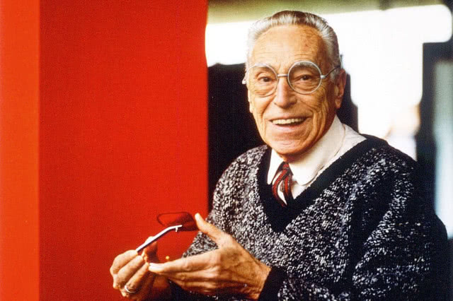 uśmiechnięty mężczyzna w swetrze na czerwonym tle