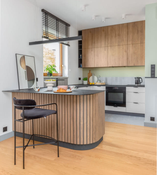 W całym mieszkaniu zastosowano rolety marki AMKO. Półwysep  kuchenny  oświetla wyjątkowa lampa, Over,  Lira Lighting.
