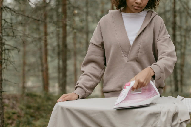 kobieta prasująca tkaninę na desce do prasowania