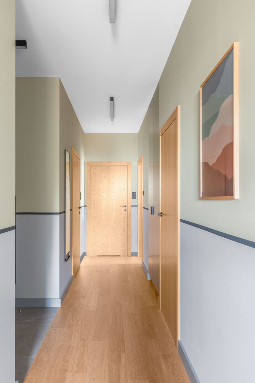 Rytm korytarza wyznaczają piony drzwi Asilo,...