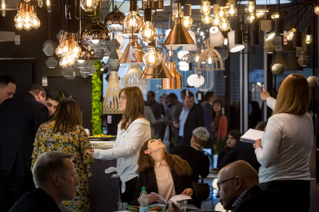 różnorodne lampy sufitowe, ciemne ściany, kanapa, stoły, krzesła