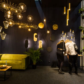 różnorodne lampy sufitowe, ciemne ściany, kanapa, stoły, krzesła