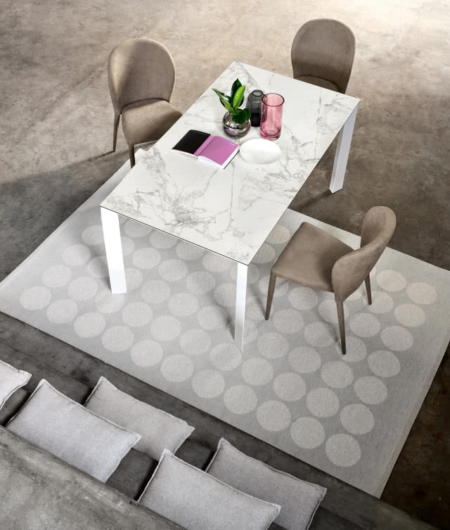 Laminam, kolekcja I-NATURALI, wzór Invisible White, stół z blatem ze spieków kwarcowych, krzesła, kanapa, dywan, notes, szklanki, wazon z kwiatem