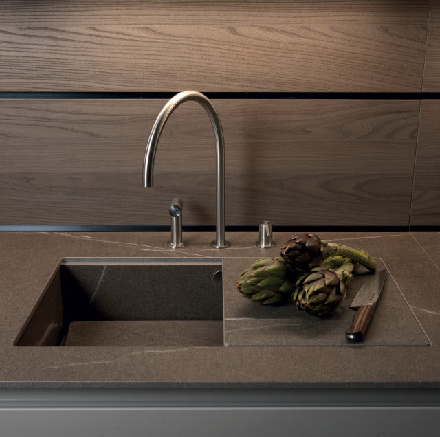 blat i umywalka ze spieku kwarcowego, warzywa, nóż, srebrna bateria zlewozmywakowa, drewniane panele na ścianie