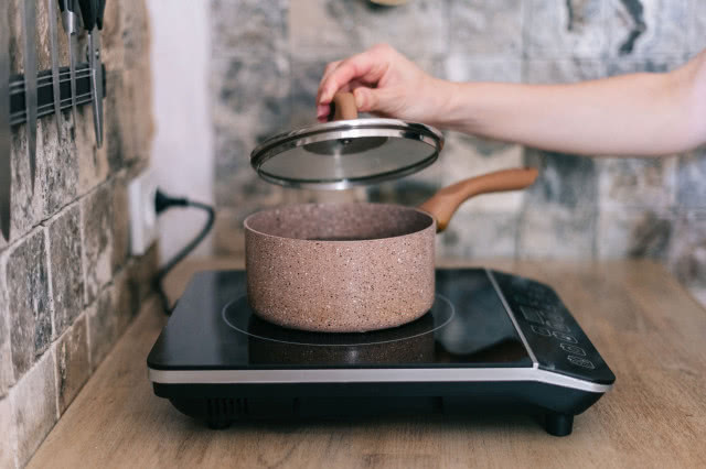 cegła na ścianie, kuchenka elektryczna, garnek, pokrywka