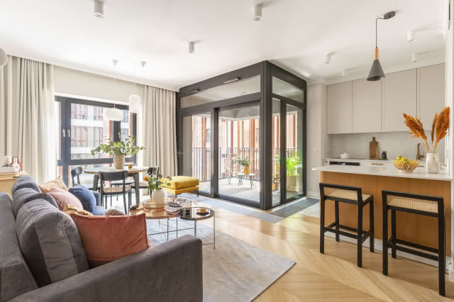 beżowy salon z kolorowymi meblami i industrialnymi oknami