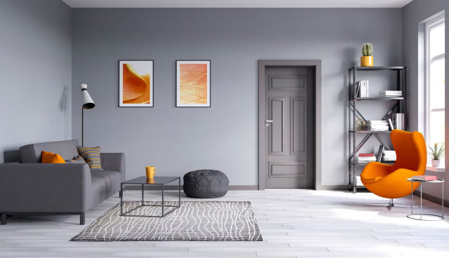 szare drzwi do salonu, szara kanapa, pomarańczowy fotel, regał, stoliki kawowe, puf, dywan, obrazy, lampa podłogowa, kaktus
