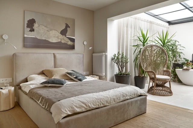 Beżowa sypialnia w stylu Bali z plecionym fotelem i zielonymi roślinami