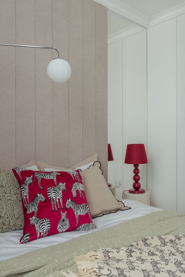 tapicerowany zagłówek łóżka w sypialni i czerwona lampka nocna
