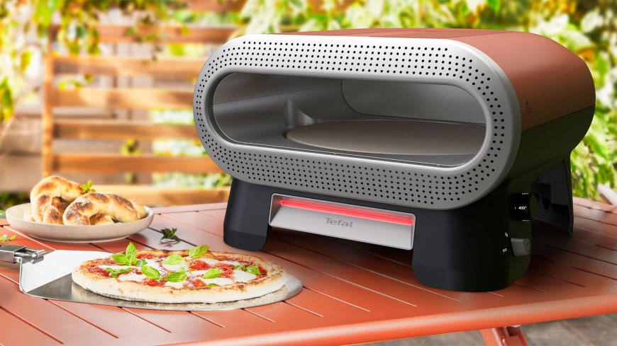 Tefal Pizza Pronto JM600TE0 – elektryczny piec do pizzy z obrotowym kamieniem, ustawiony na tarasie obok świeżo upieczonej pizzy.