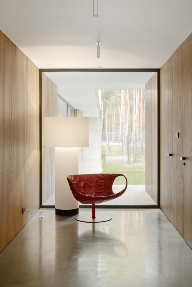 brązowy skórzany designerski fotel, obok niego biała lampa