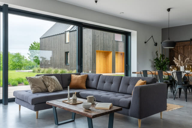 Zdjęcie salonu z dużymi oknami i szarą sofą