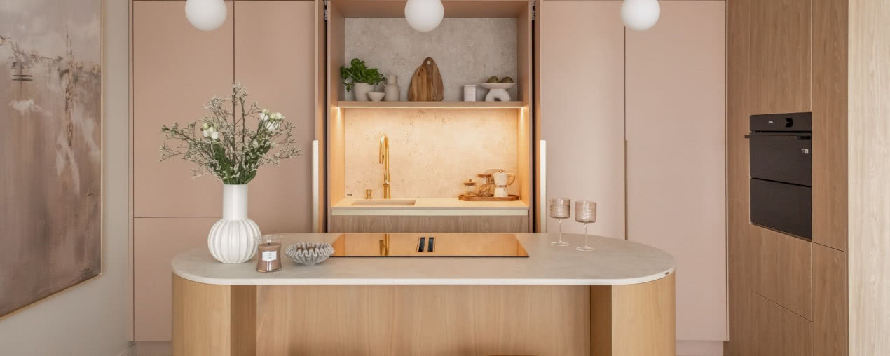 Przyjazna kuchnia z wyspą w dwóch kolorach: beż i róż otulają spokojem