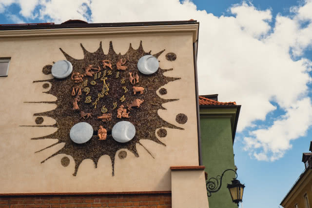 Zegar z mozaikową tarczą na elewacji budynku przy Piekarskiej.