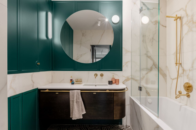 Łazienka z zielonymi ścianami, płytkami z marmuru i złotymi dodatkami