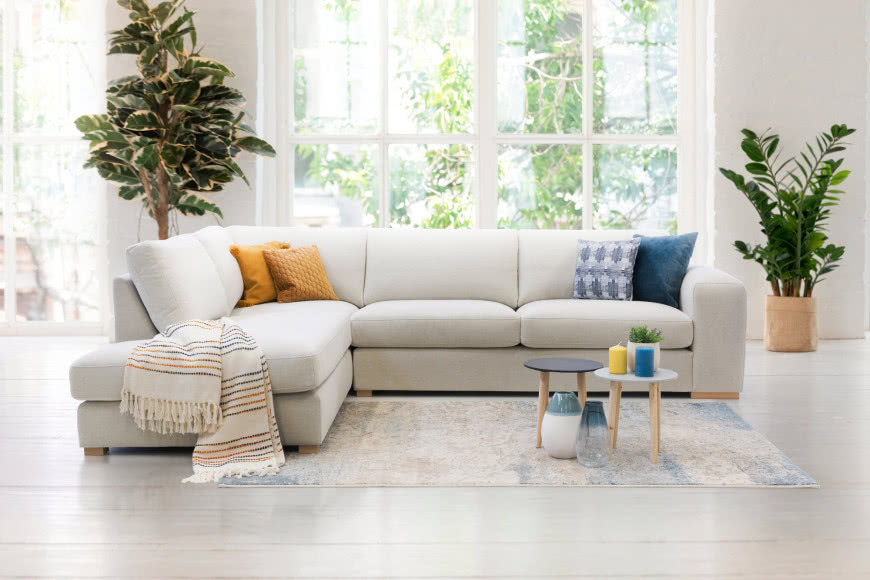 Klasyczna forma modelu PINET marki Livingroom narożnik, duże kwiaty, poduszki ozdobne, stoliki kawowe, świece, koc, dywan