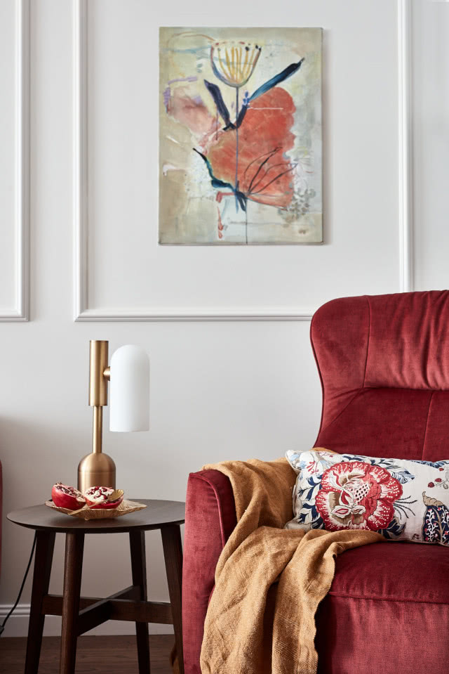 Salon ze sztukaterią na ścianach i bordową kanapą w welurze