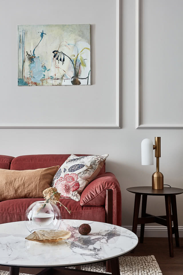 Salon ze sztukaterią na ścianach i bordową kanapą w welurze