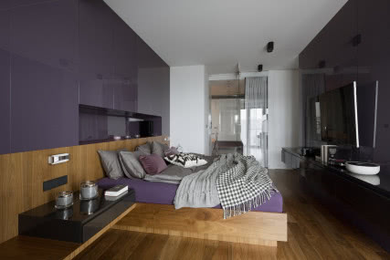 W sypialni dominuje fiolet. Na ścianach ułożone są kolorowe panele szkła lacobel.
